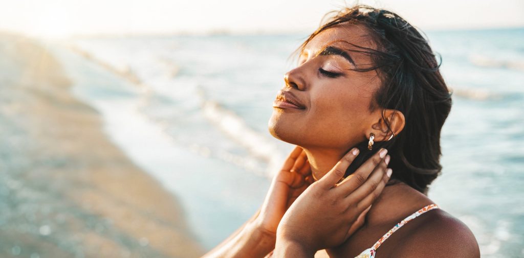 Peaceful black woman enjoying sun light at the beach